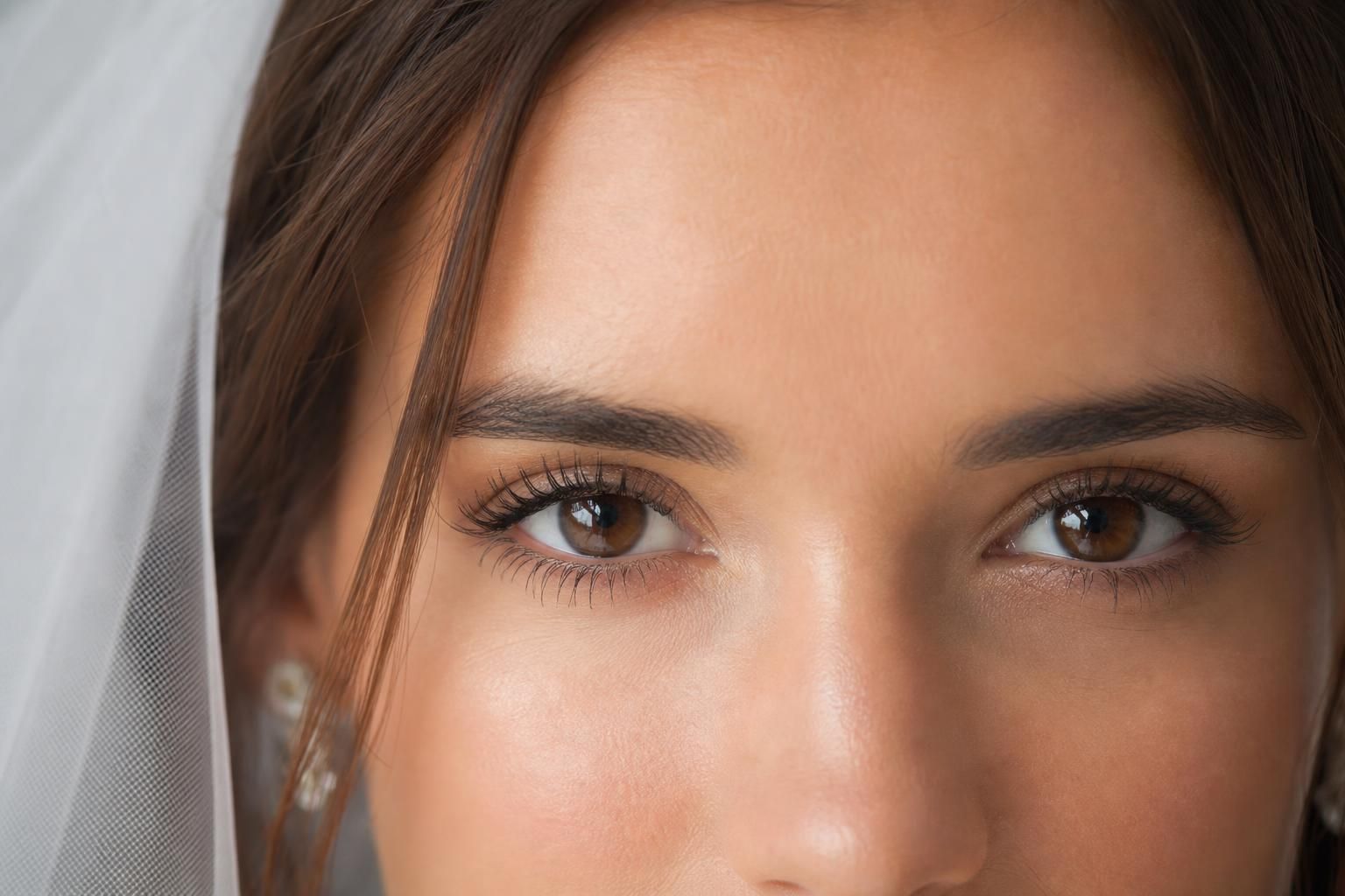 Gros plan sur le regard d'une mariée aux yeux marron avec maquillage nude et cils allongés au mascara