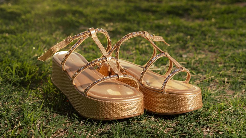 Sandales compensées dorées ornées de strass sur l’herbe