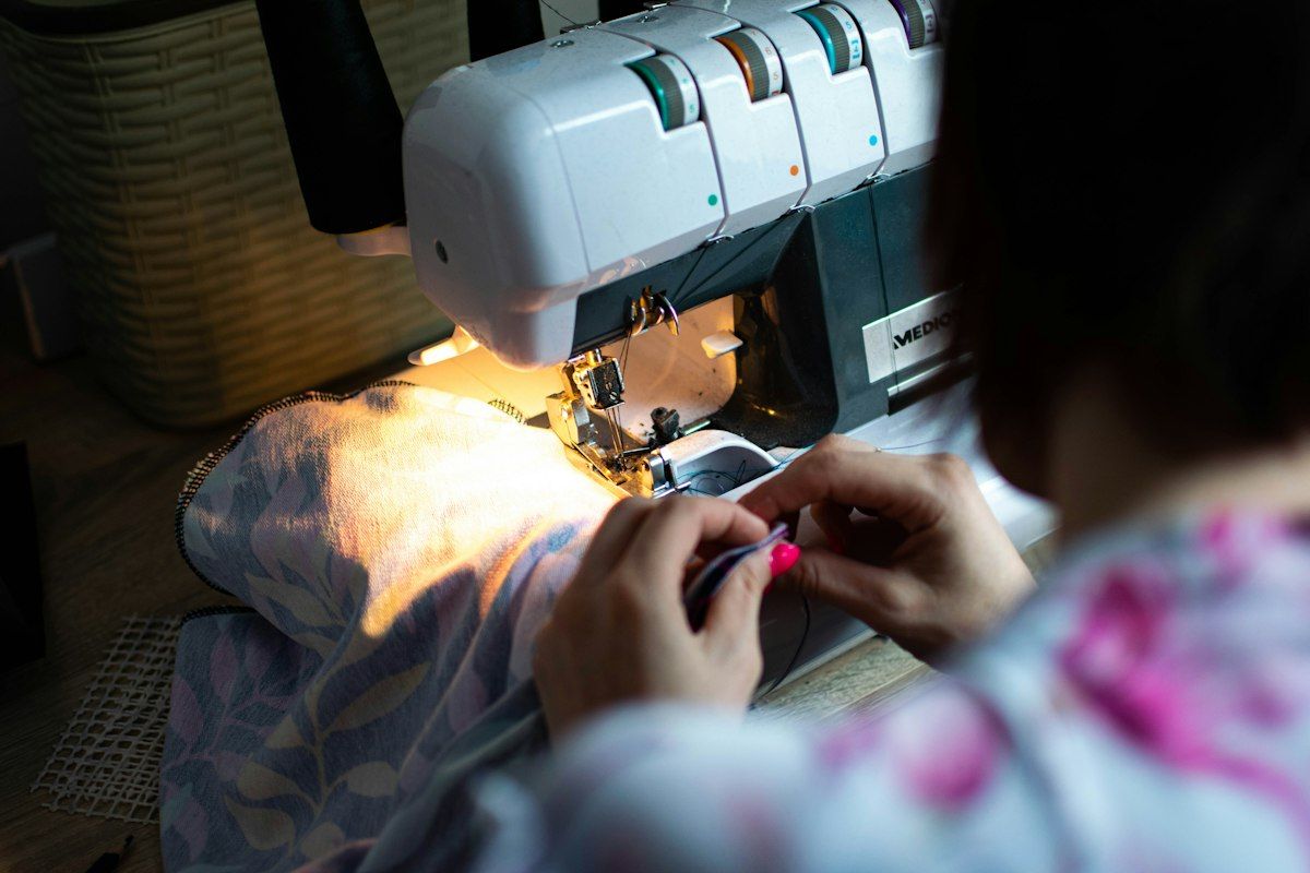 Couturière guidant un tissu sous le pied presseur d'une surjeteuse 4 fils